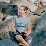 Man reading book with blue believe button short-sleeve t-shirt in gray white finger clicking and John 3:16 above