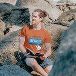 Man reading book with blue believe button short-sleeve t-shirt in orange white finger clicking and John 3:16 above