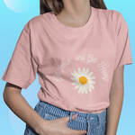 female model wearing pink shirt with text " get Jesus get happy " in an arch above a daisy flower white petals yellow center